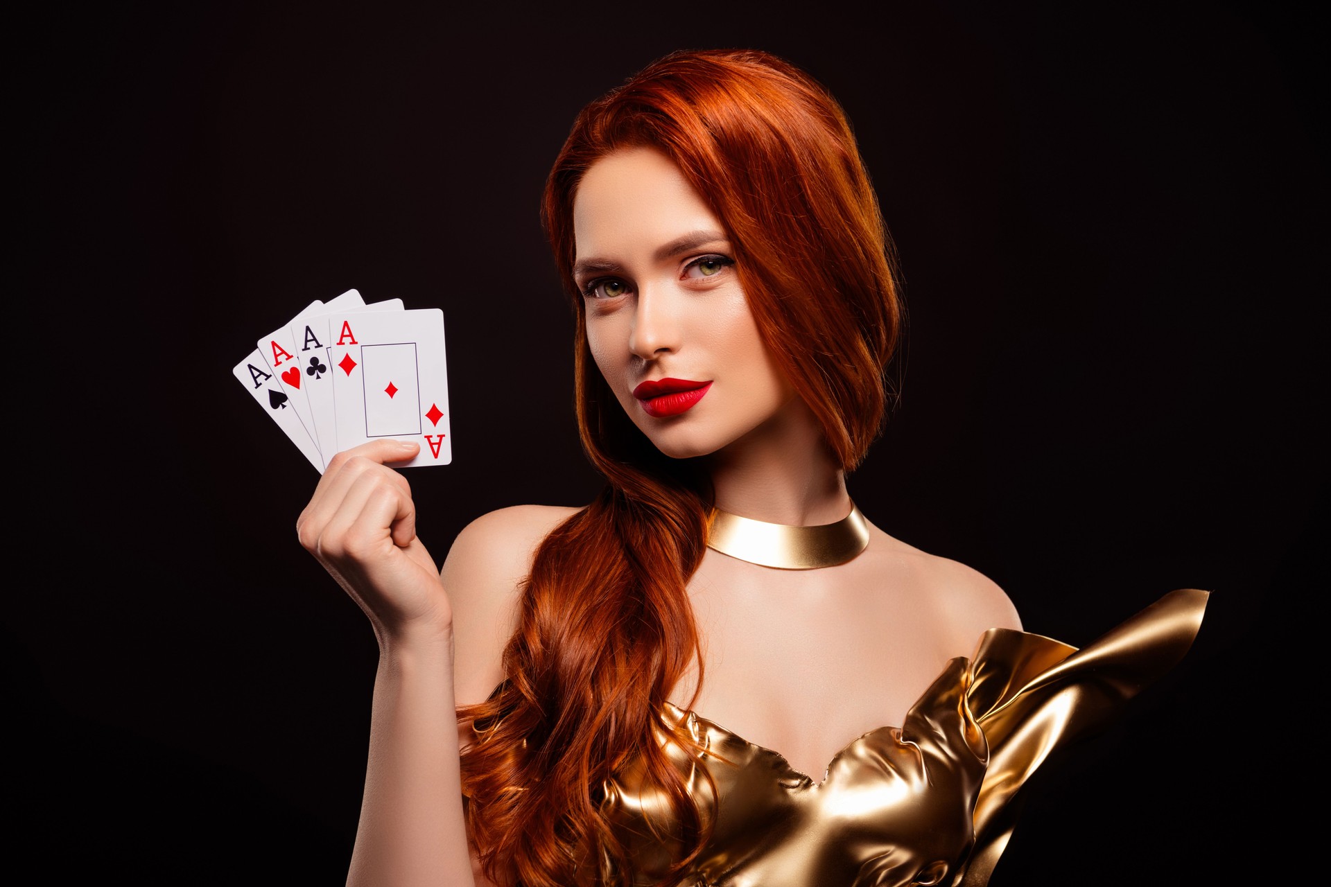 Rich woman in a golden dress holding playing cards with a confident and glamorous expression